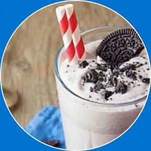 “Cookies & cream milkshake served in a tall glass with whipped cream and cookie pieces.”