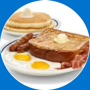 “Breakfast plate with a mix of eggs, meat, and pancakes.”